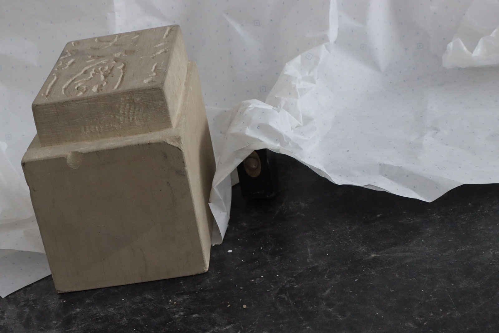 Hand-carved sandstone seal block beside pattern paper in the Städelschule installation